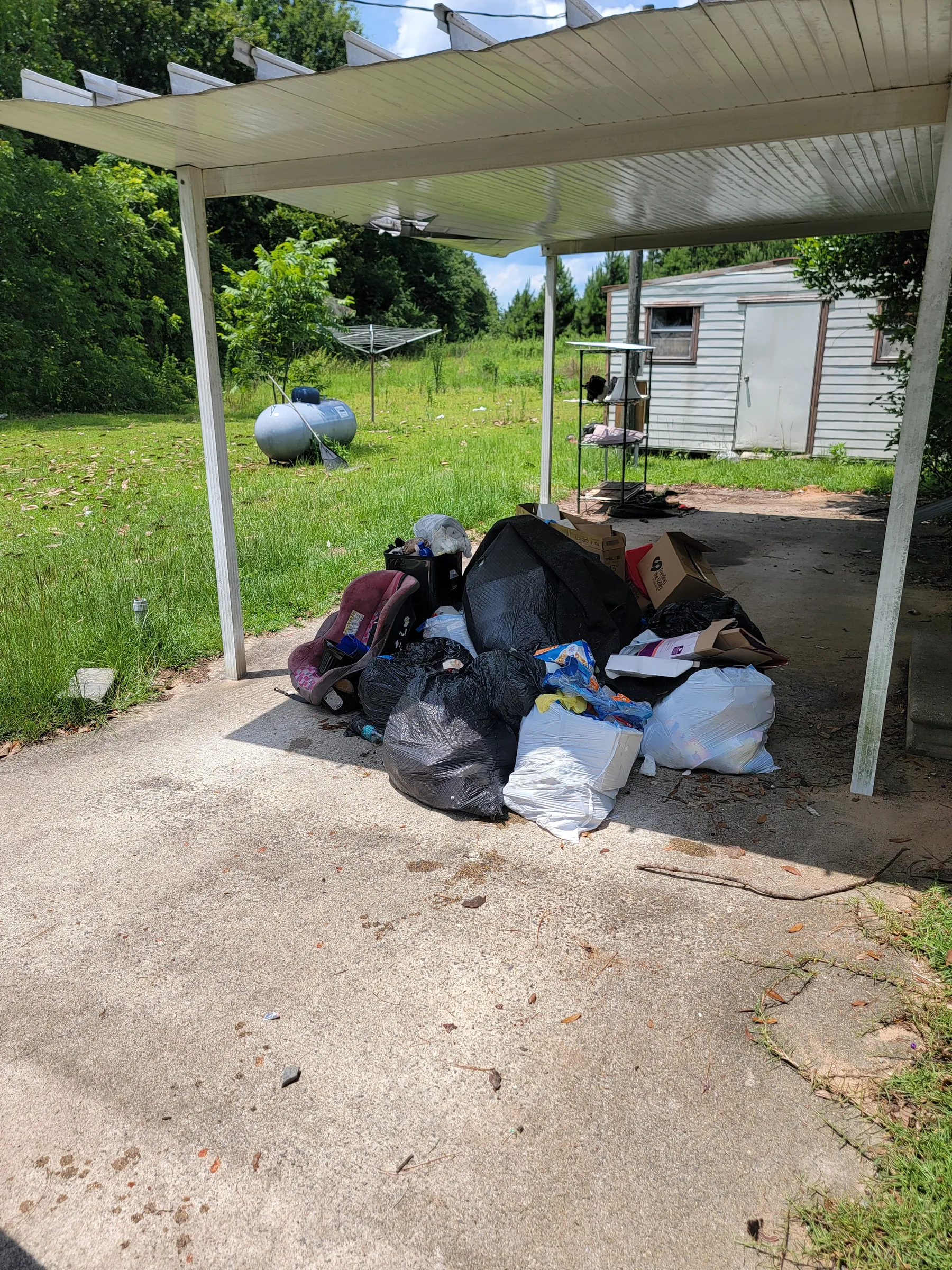Bags and unwanted items in a carport before pickup