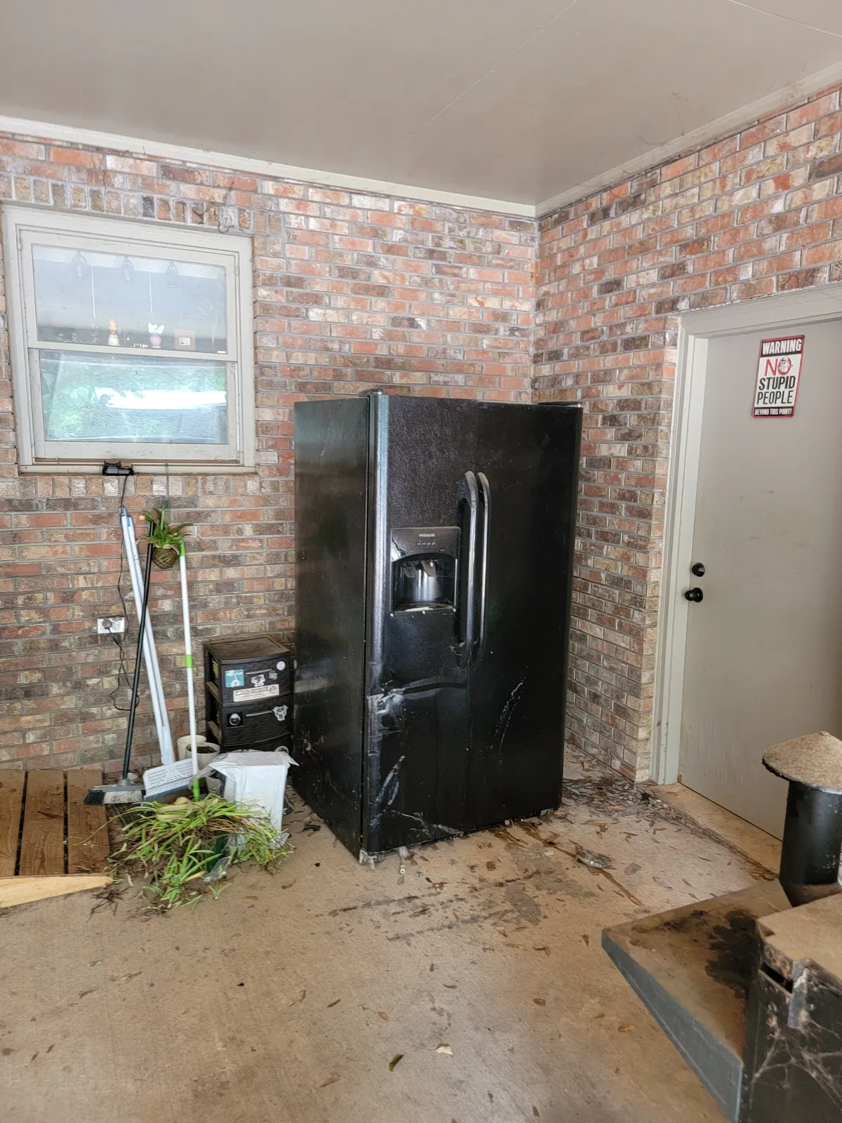 An unwanted refrigerator on a brick porch before pickup